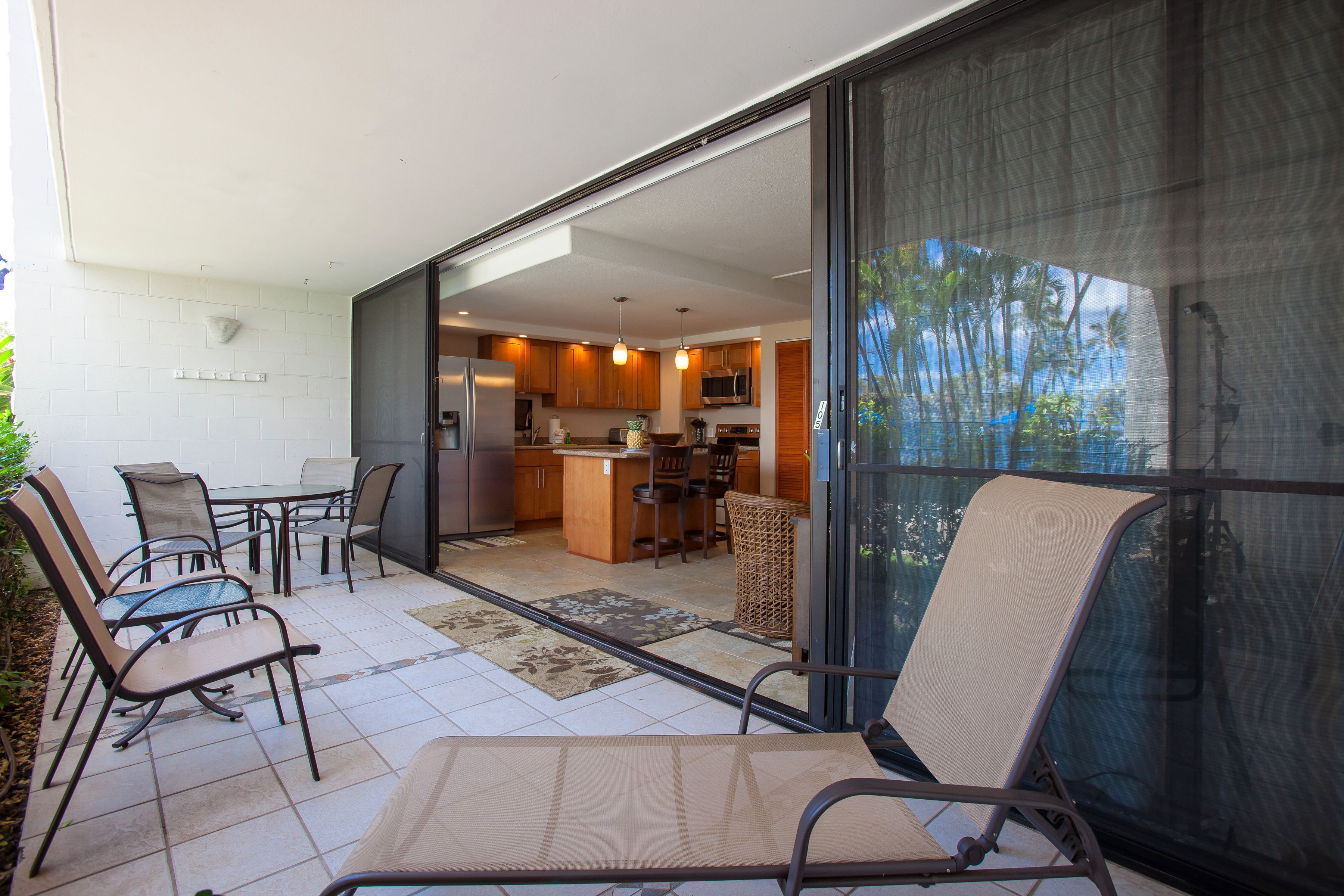 A modern kitchen with a large island, sliding glass doors leading to an outdoor patio with seating.