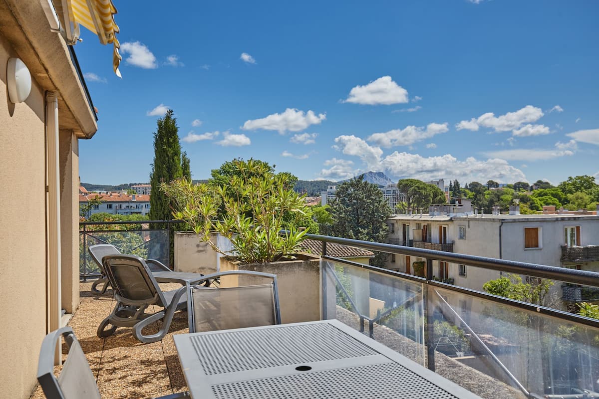 A balcony with outdoor seating, a potted plant, and a view of the cityscape.