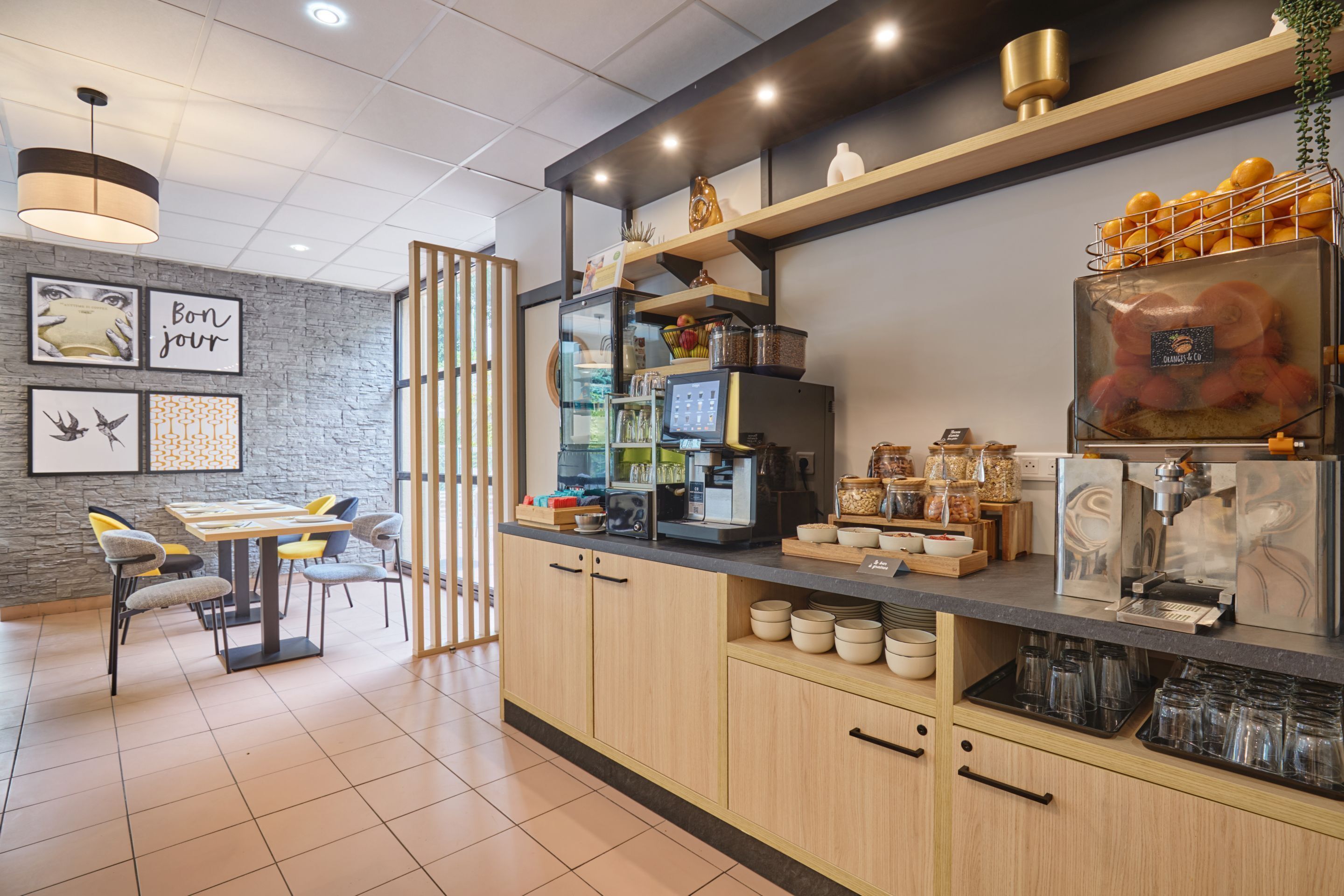 A modern kitchen with a coffee machine, a fruit display, and a dining area with chairs and a table.