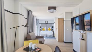 Een moderne hotelkamer met een bed, een bureau, een televisie en een zithoek.