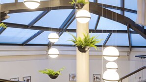 Un interior moderno con techo de vidrio, varias lámparas colgantes y plantas de interior.