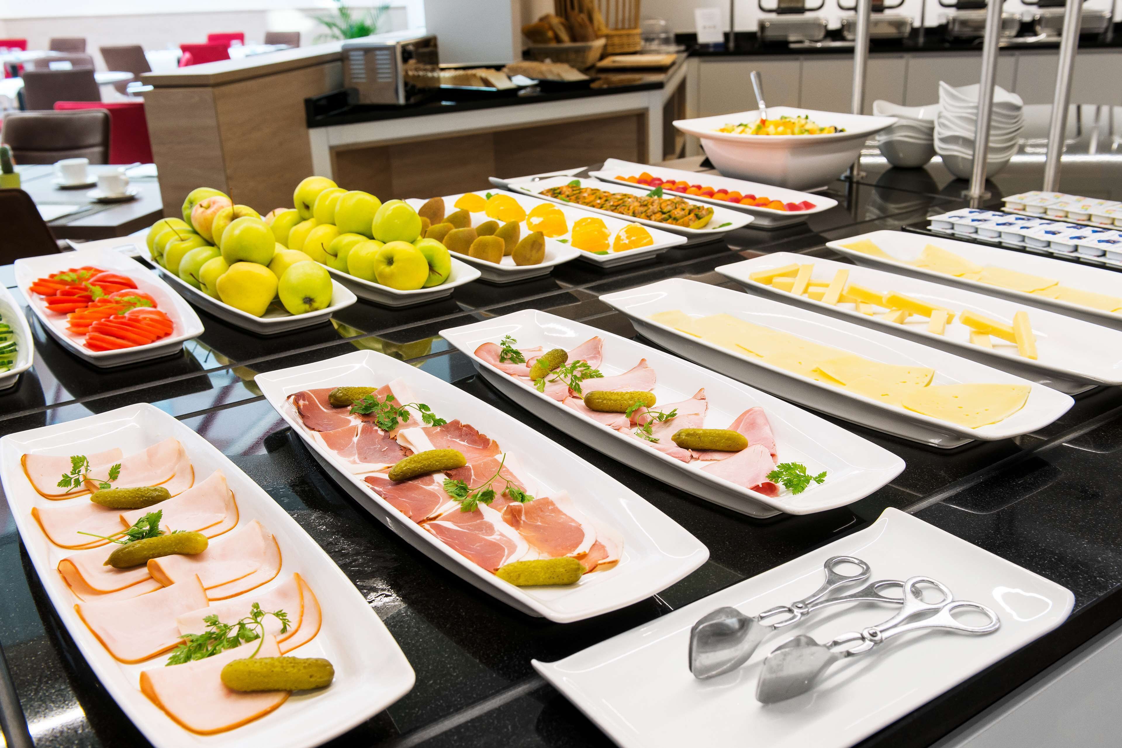 Una mesa de buffet con diversos alimentos, como frutas, quesos y embutidos.