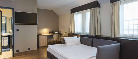 A modern hotel room with a bed, a desk, and a TV.