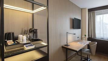 Habitación de hotel con escritorio, silla y televisor de pantalla plana montado en la pared.