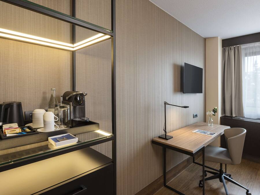 Habitación de hotel con escritorio, silla y televisor de pantalla plana montado en la pared.
