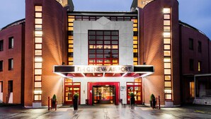 El exterior del Hotel NH Geneva Airport, con una entrada destacada, ventanas amplias y fachada de ladrillo.