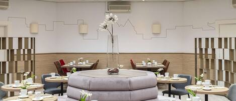 A modern interior with a central seating area, round tables, and a high ceiling with skylights.
