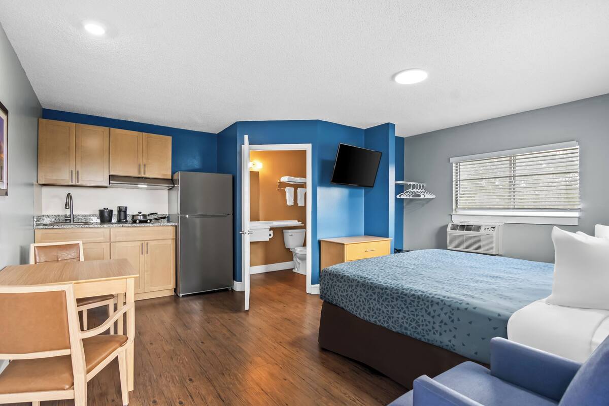 A compact room with a kitchenette, a bed, and a bathroom.