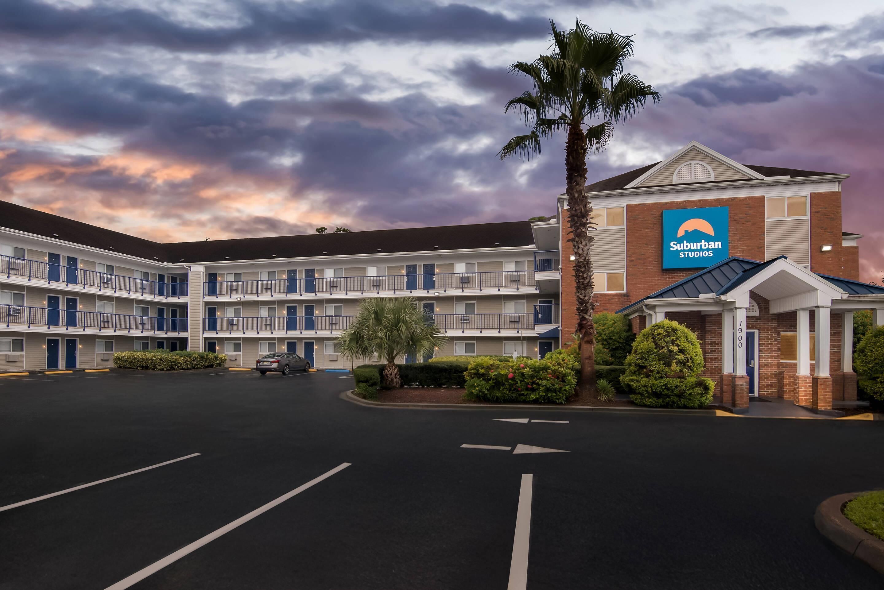 Un motel con estacionamiento, un edificio de un solo piso y un letrero de Suburban Studios.