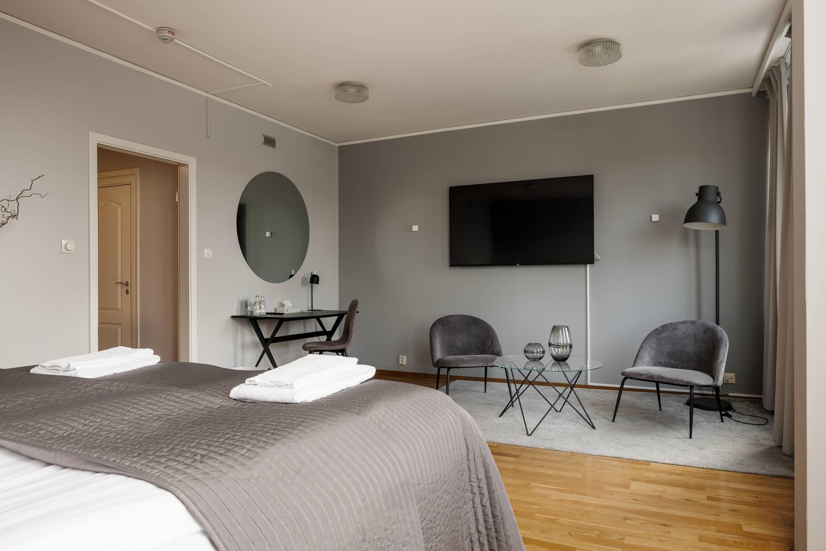 Ein Hotelzimmer mit Bett, Schreibtisch, zwei Stühlen, Fernseher und Lampe.