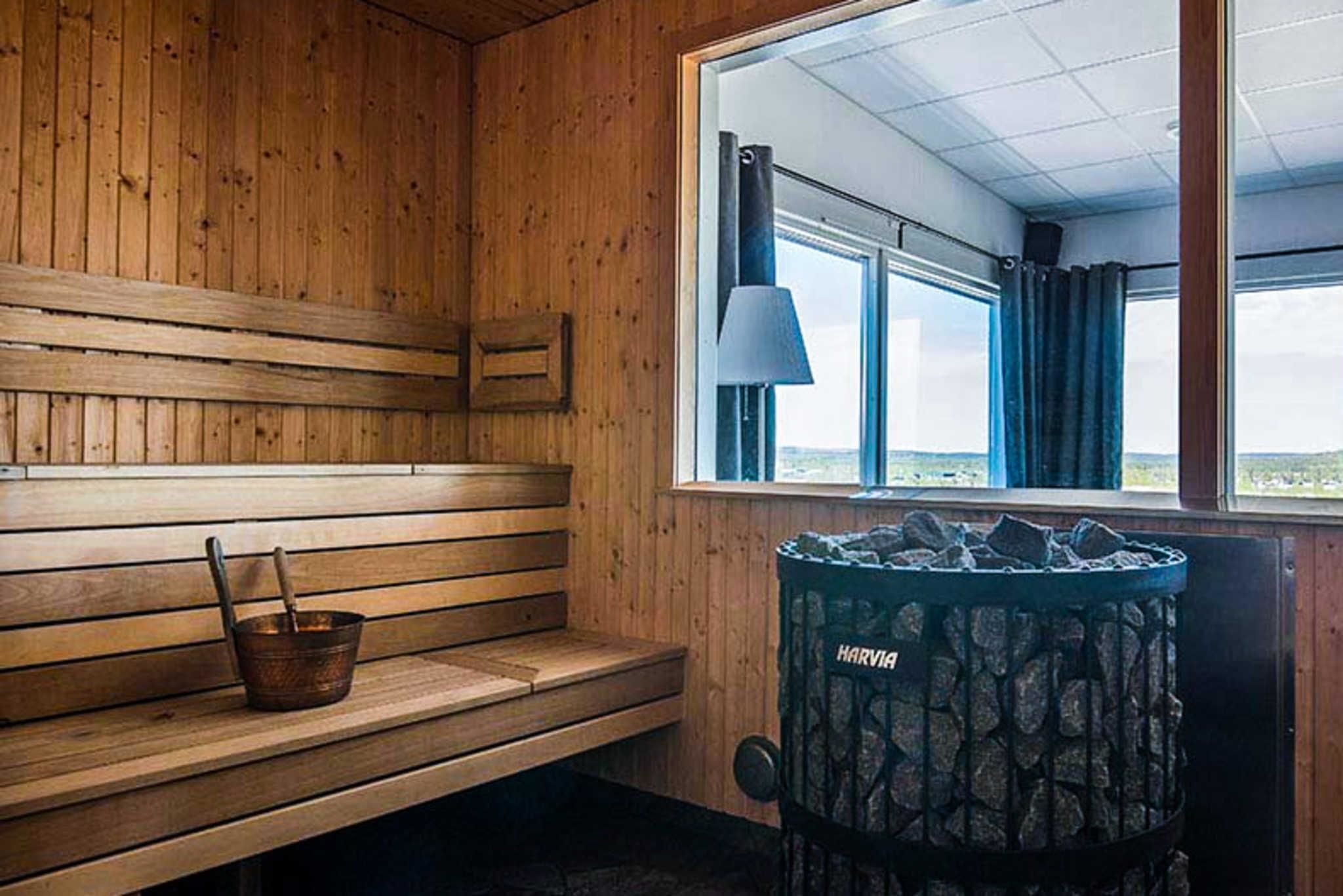 A wooden bench, a window with a view, and a stone heater labeled "HARVIA".