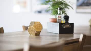 A wooden dining table with hexagonal decorative items, a potted plant, and a bottle on a black box.