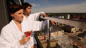 A balcony with a city view, a glass of red drink, and a person in a white robe. - Quality Hotel Bodensia (Boden)
