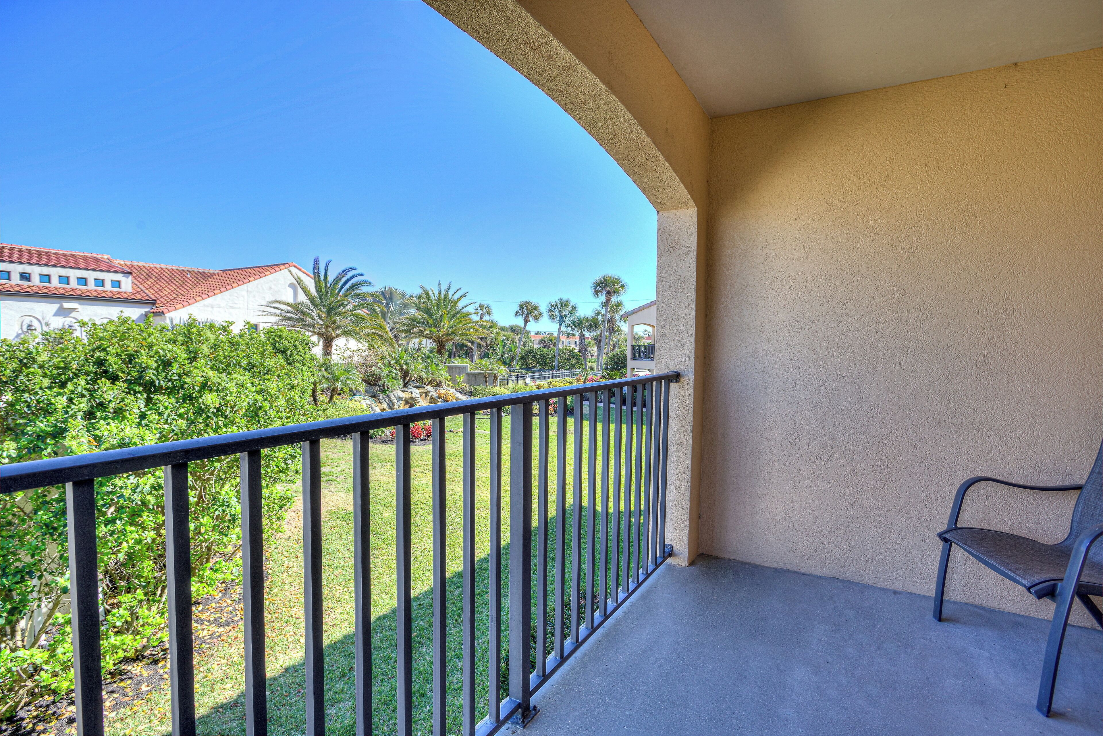 A balcony with a view of a landscaped area and buildings in the background.
