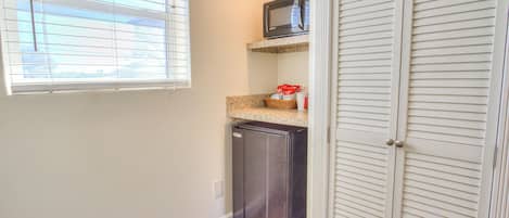 A compact kitchen with a refrigerator, microwave, and a small countertop.