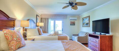 A hotel room with two beds, a television, a ceiling fan, and a window with curtains.