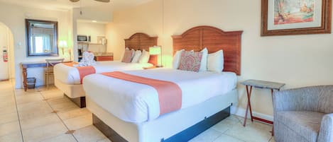 Une chambre d’hôtel avec un grand lit, un bureau, une chaise et un ventilateur de plafond.