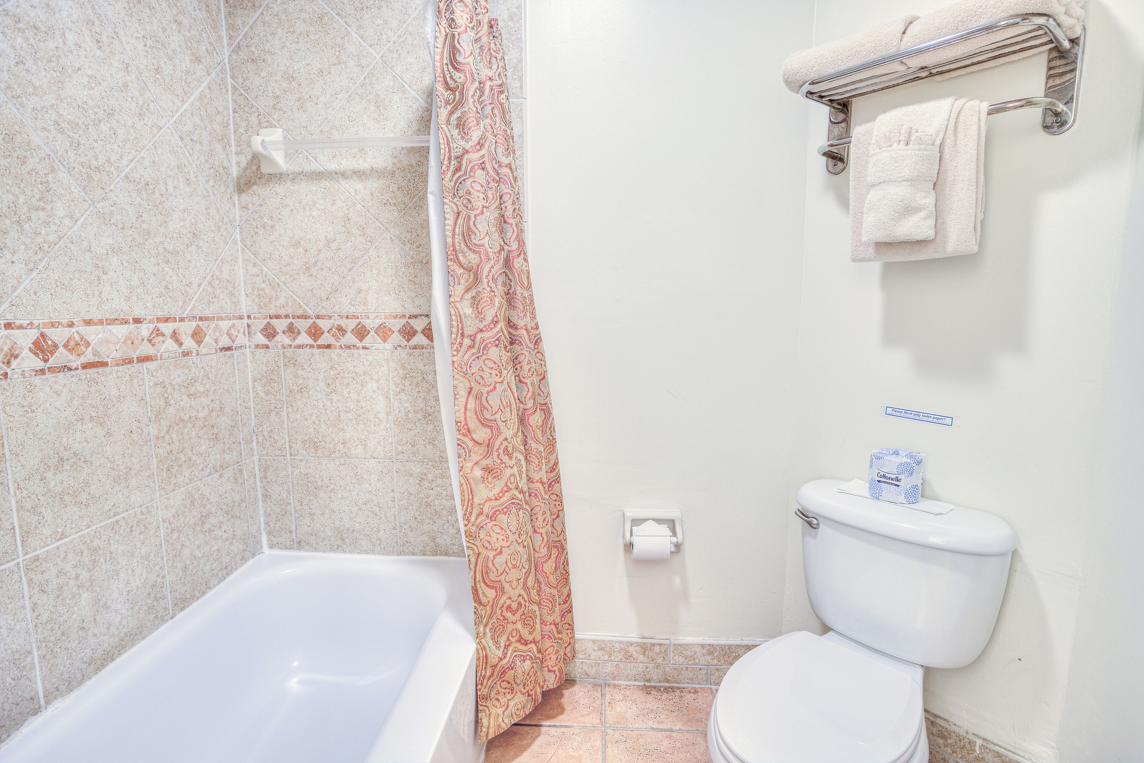 A bathroom with a bathtub, toilet, and shower curtain.