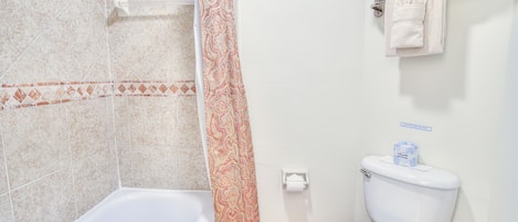 A bathroom with a bathtub, toilet, and shower curtain.