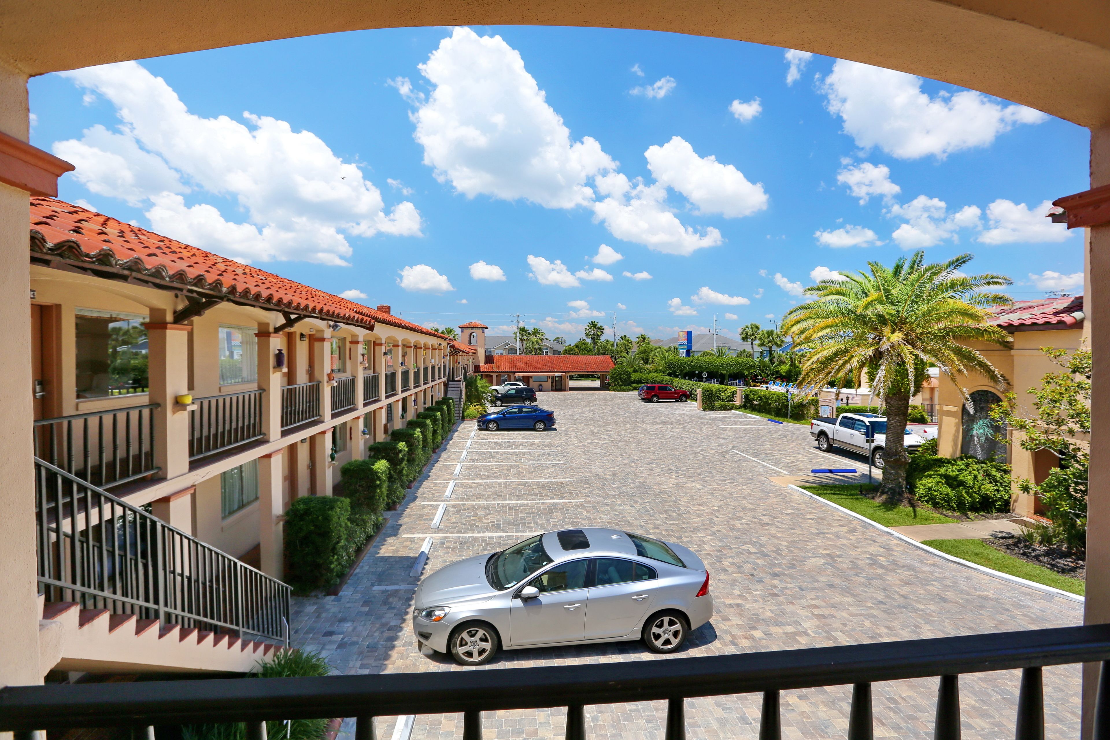 Ein Hotel mit Parkplatz, mehreren Autos und blauem Himmel mit Wolken.
