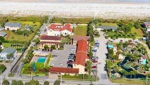 Vue aérienne d’un hôtel situé sur la côte, avec une piscine, un parking et un accès à la plage.