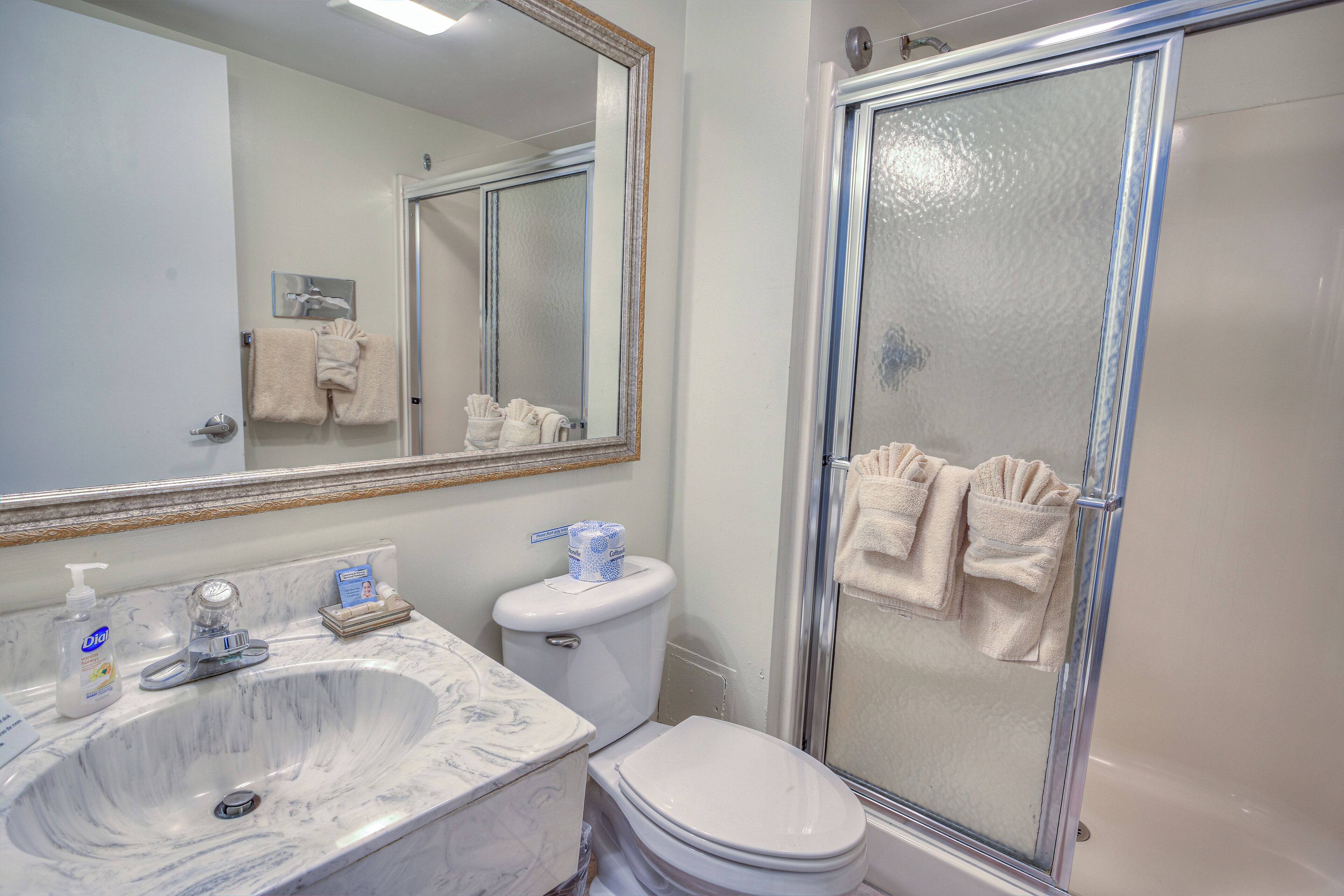 A bathroom with a marble sink, toilet, and glass shower enclosure.