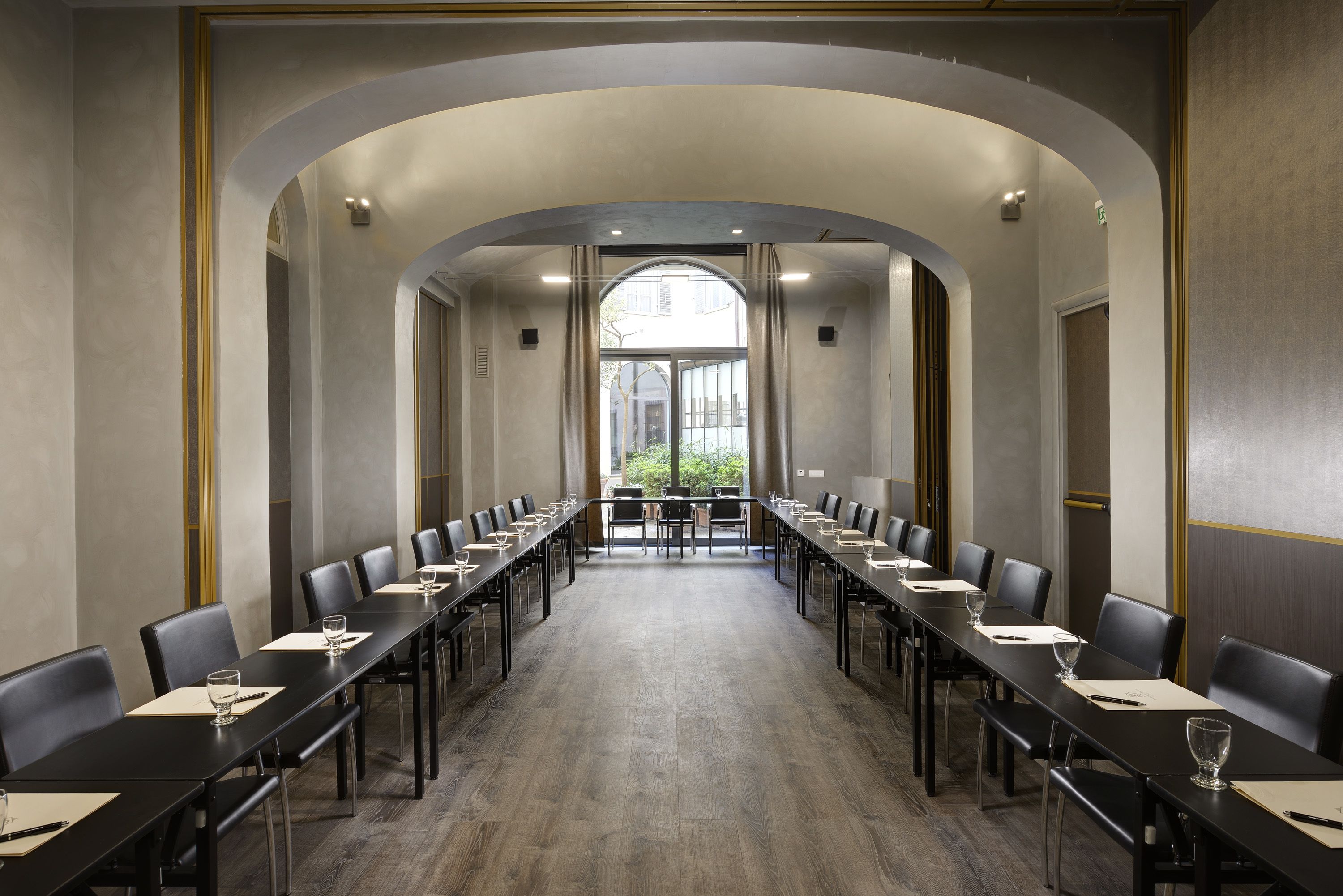 Een vergaderruimte met lange tafels en stoelen, een gewelfd plafond en grote ramen.