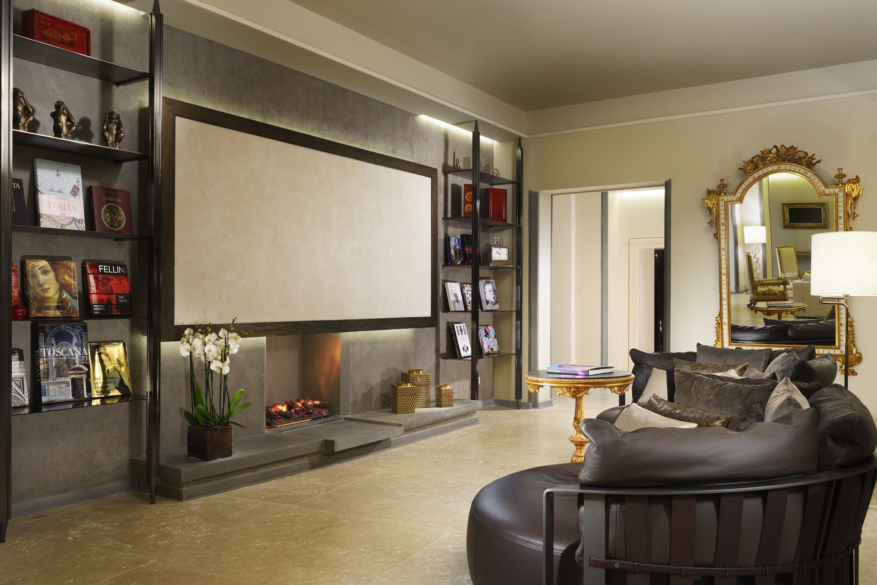 A living room with a fireplace, bookshelves, a sofa, and a mirror.