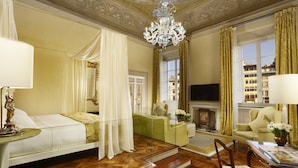 Un dormitorio lujoso con cama, una zona de estar con sofá y sillones, televisión y chimenea.