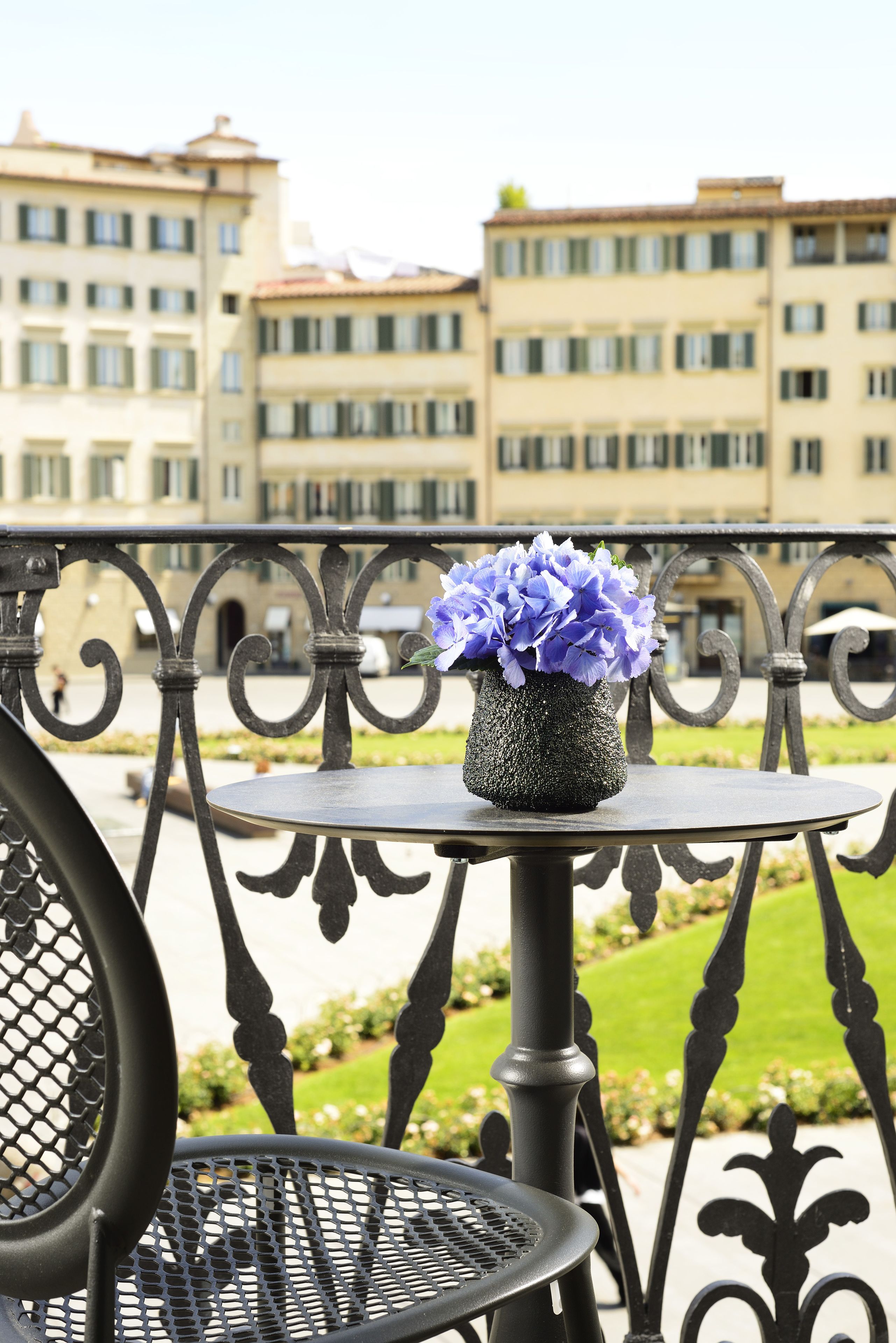 Un balcon avec une table ronde et un vase de fleurs.