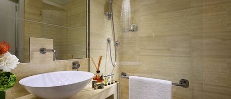Un baño moderno con un lavamanos grande de color blanco, una ducha con cerramiento de vidrio y un espejo sobre el lavamanos.