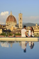 A couple by a pool with a view of a historic building.