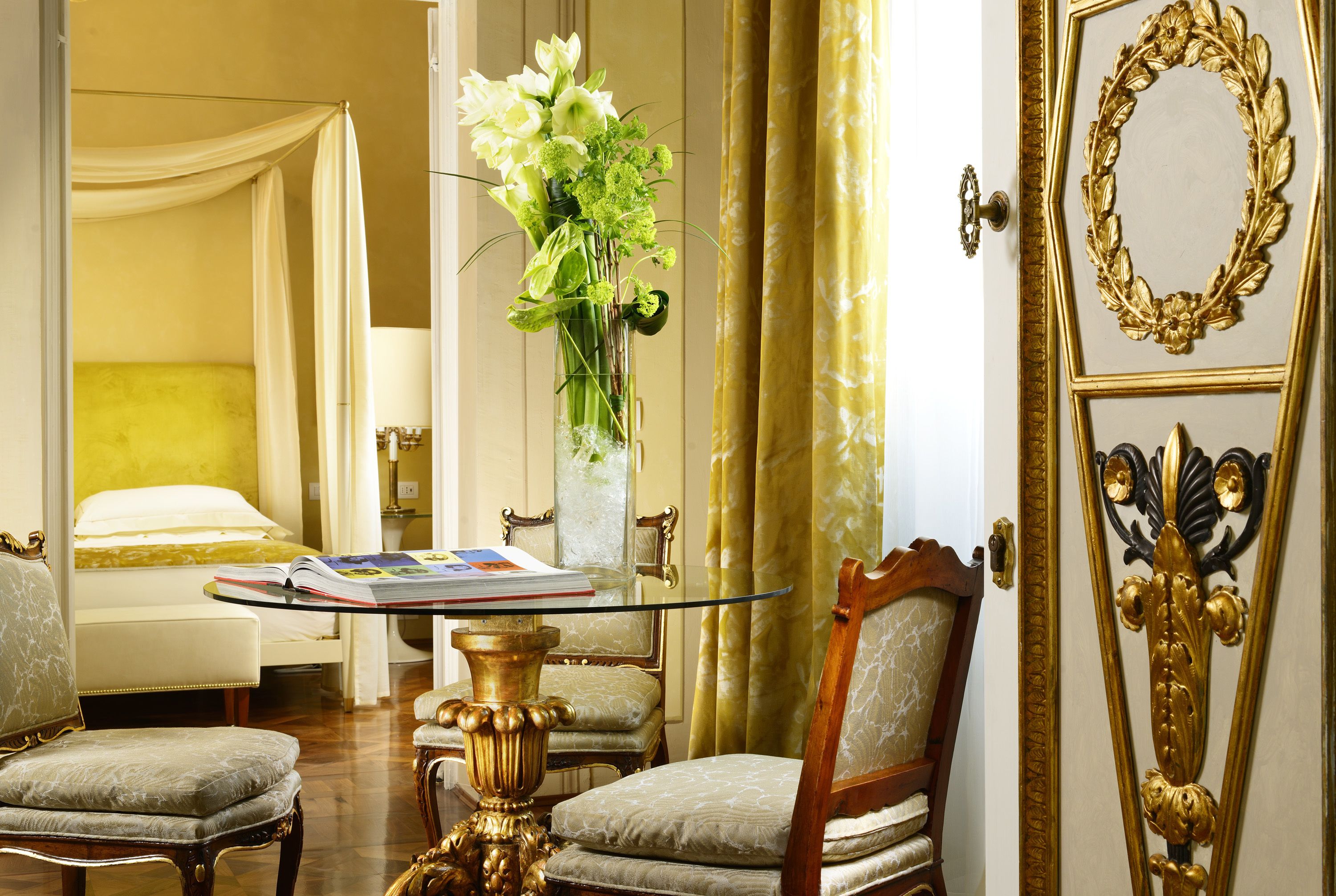 Una stanza con un letto, una zona relax con una sedia e un tavolino, e uno specchio decorativo.