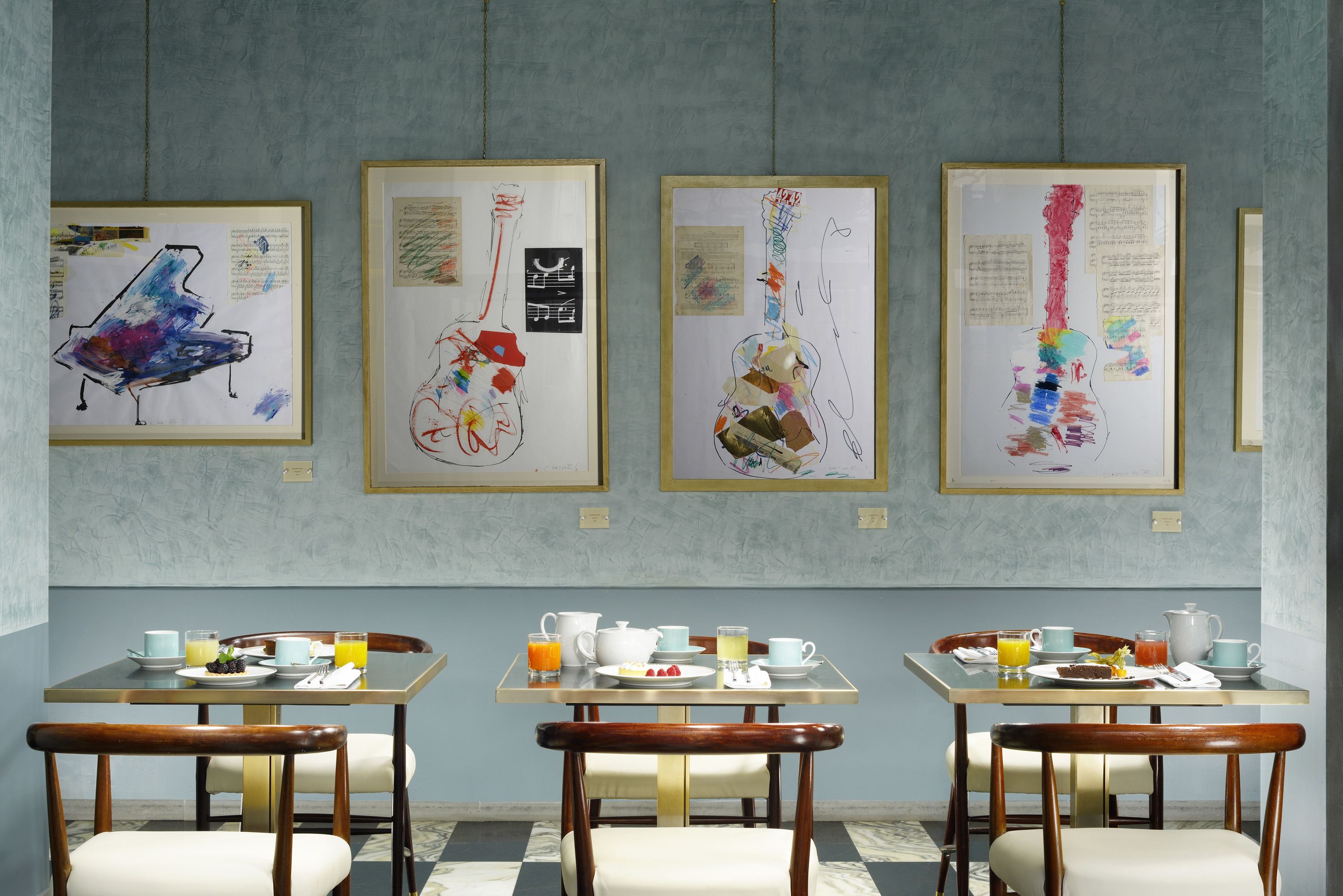 A dining area with tables set for breakfast, featuring artwork on the walls.