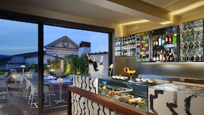 Zona de bar moderna con cerramiento de vidrio, una variedad de botellas y vistas a un edificio con una torre de reloj.
