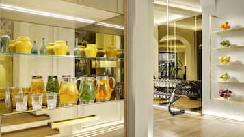 A modern interior with a glass display of yellow and green vases, a mirrored wall, and a wooden floor.