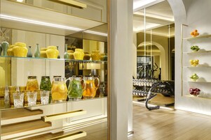 A modern interior with a glass display of yellow and green vases, a mirrored wall, and a wooden floor.
