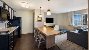 A modern kitchen with a dining area, a flat-screen TV, and a view of the city. - Sonesta Simply Suites Jersey City (Jersey City)