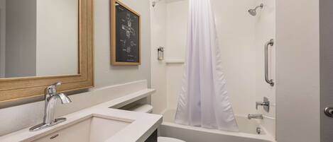 A modern bathroom with a sink, toilet, and bathtub.