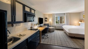 A hotel room with a kitchenette, a bed, a desk, and a window with curtains. - Sonesta Simply Suites Jersey City (Jersey City)