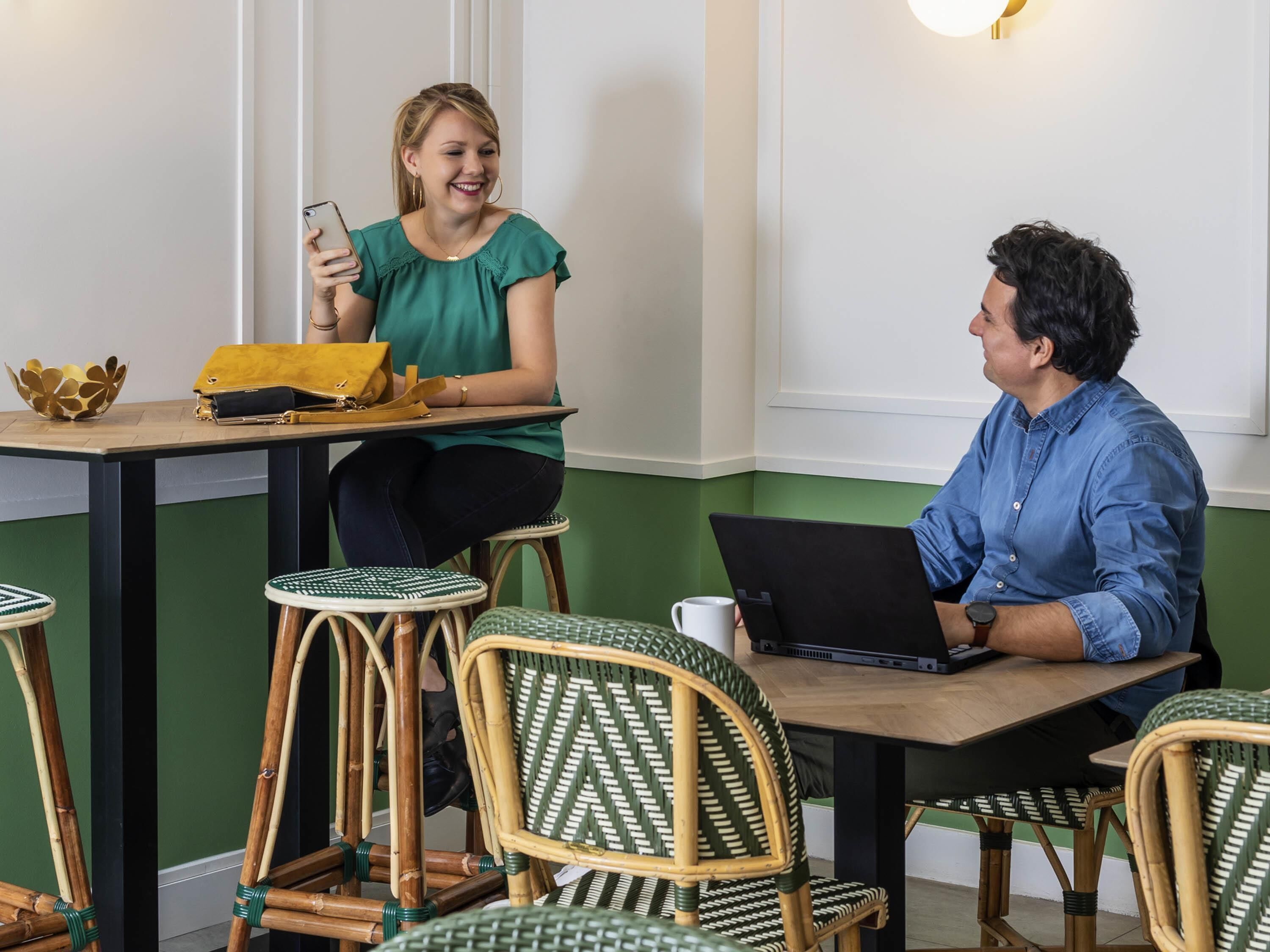 A room with a table, chairs, a laptop, and a smartphone.