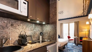 A compact hotel room with a kitchenette, a bed, a desk, and a view of the city. - Aparthotel Adagio Paris Haussmann (Paris)