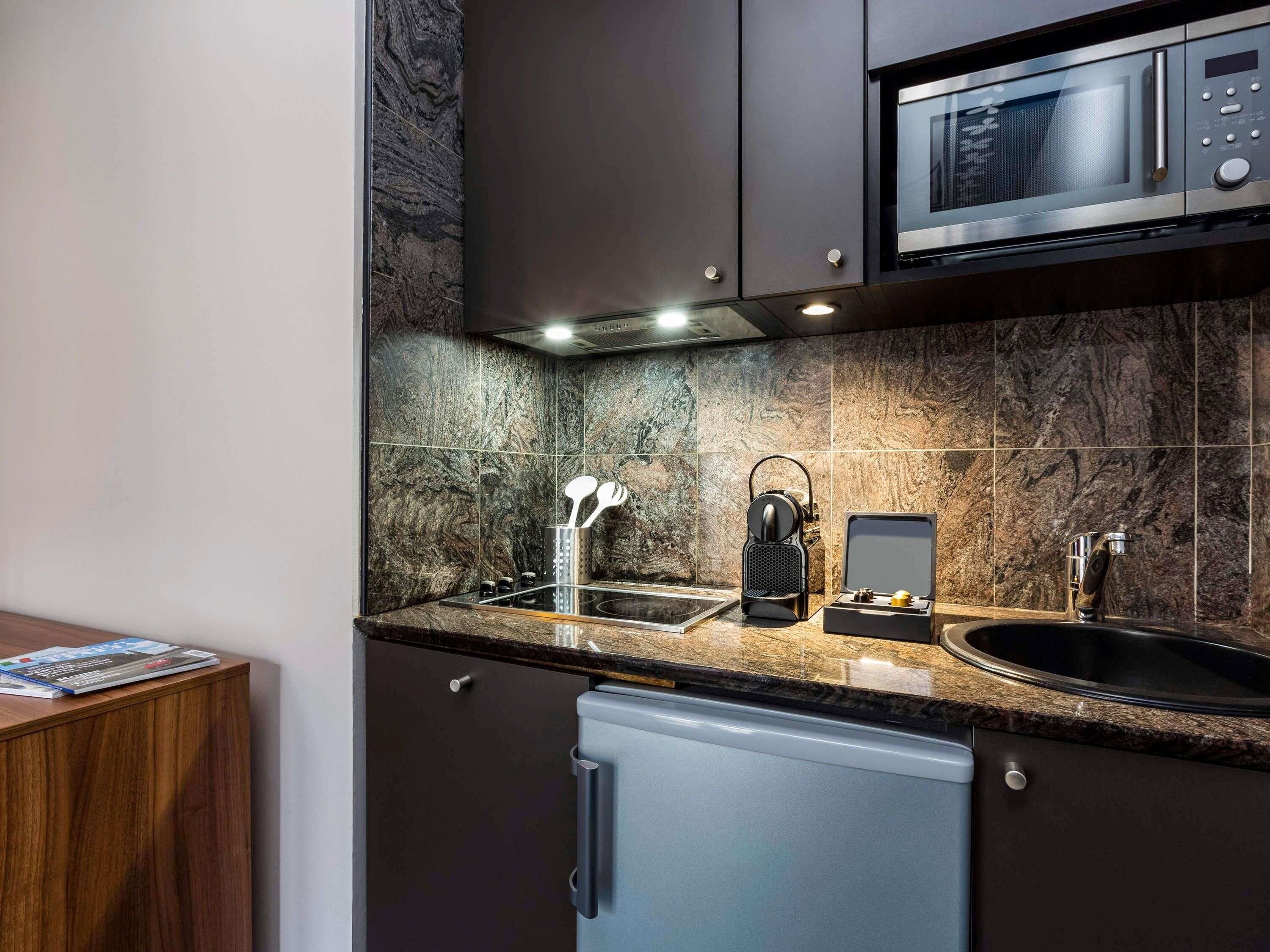 Una cocina moderna con microondas integrado, cafetera y lavabo.