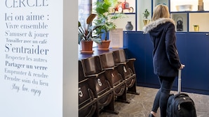A hotel reception area with a blue interior, a welcome sign, and a woman with a suitcase. - Aparthotel Adagio Paris Haussmann (Paris)