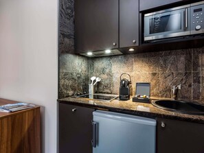 Una cocina moderna con microondas integrado, cafetera y lavabo.