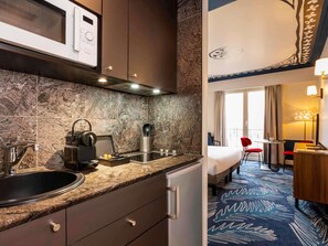Habitación de hotel con kitchenette, una cama, escritorio y vistas a la ciudad.