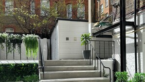 A set of concrete stairs leading to a garage door, surrounded by potted plants and a brick building in the background. - Garden View Hotel (London)
