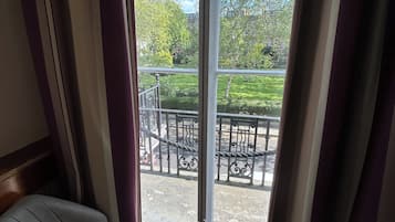 Una habitación con vista a un balcón, una silla y un ventanal con cortinas.