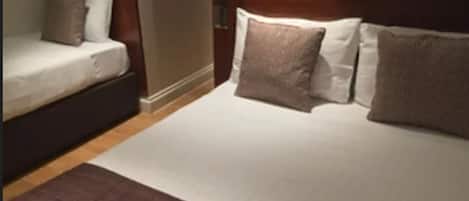 A hotel room with a large bed, a smaller sofa, and a wooden headboard.