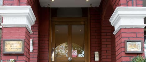 A red brick building with a wooden door and steps leading to the entrance.